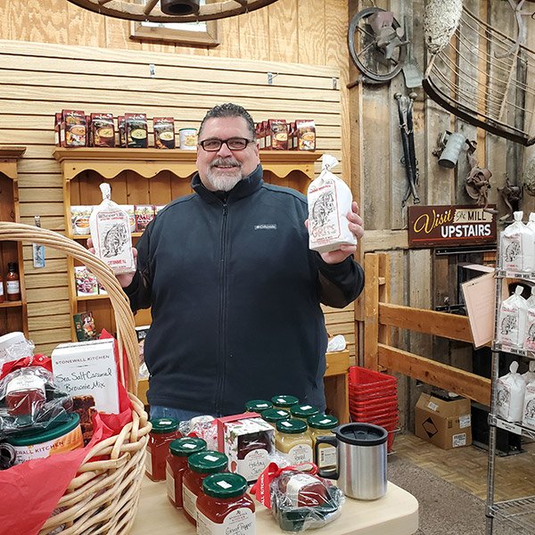 Mr. John Parker holding a bag of grits in the Saunooke's Mill store