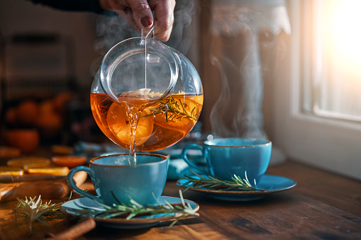 Photo of pitcher of tea being poured into blue mugs