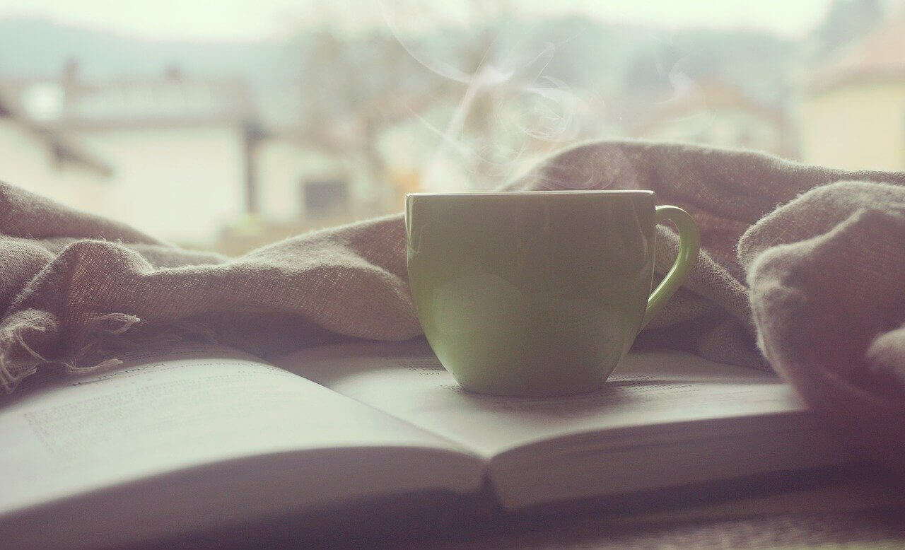 steaming mug on top of an open book