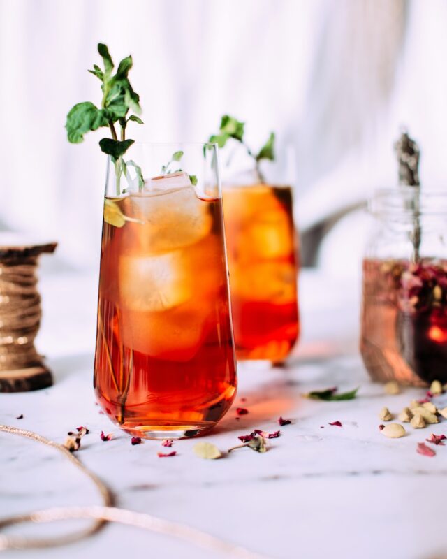 Iced tea with herb garnish on a white tablecloth and white background