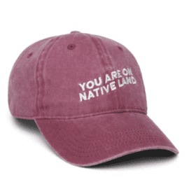Red baseball cap with white text that says YOU ARE ON NATIVE LAND