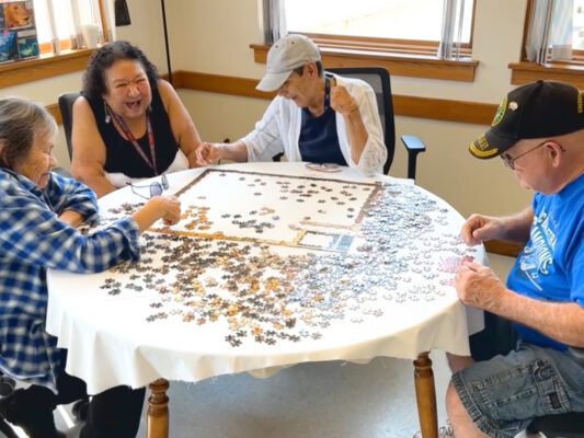 Photo of four people at Winnebago Senior Center putting a puzzle together at a table