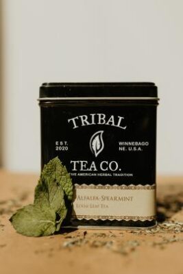 Tin of black Tribal Tea Alfalfa Spearmint on a wooden table