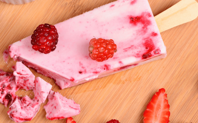 Close up of pink popsicle with berries on top