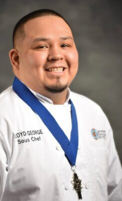 Photo of Chef Lloyd George wearing a white shirt that says "Lloyd George Sous Chef" 