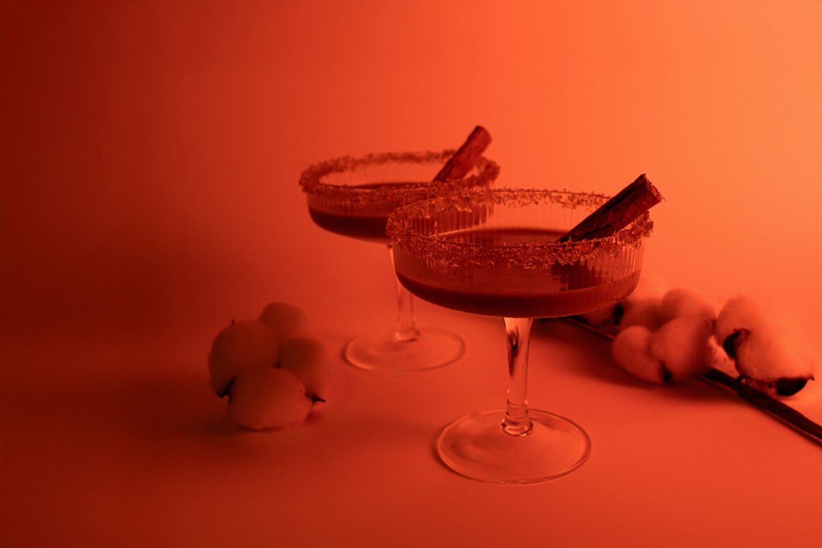 Two glasses filled with liquid sitting on top of a table with fruit