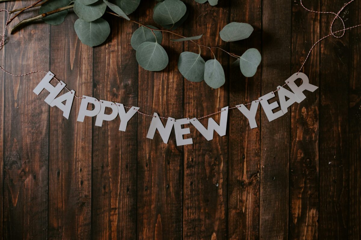 wooden background with the words HAPPY NEW YEAR and leaf decorations