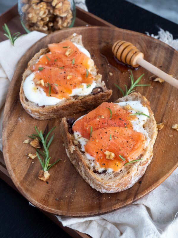 sliced bread with cream cheese and smoked salmon on a wooden cutting board