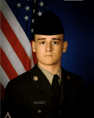 Headshot of Jackson Kennedy in Army National Guard uniform with American flag in background
