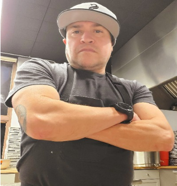 Chef Paul Molina with his arms crossed and wearing a hat